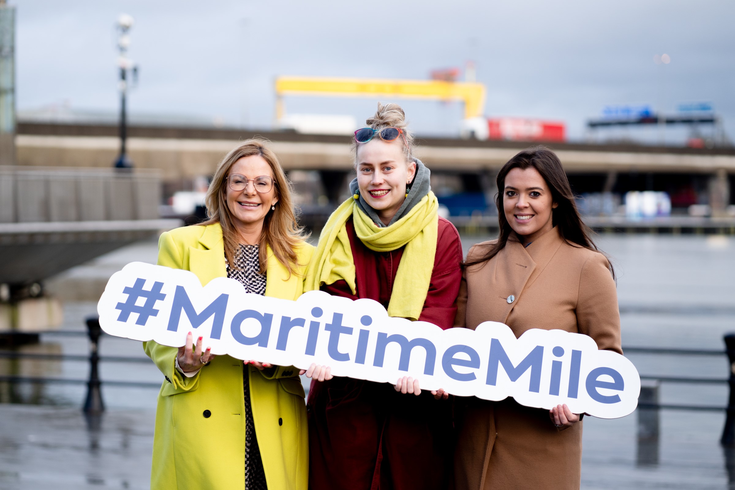 Councillor Tina Black, digital artist Katya Solomatina, and Jenna Crymble from Maritime Belfast Trust holding Maritime Belfast sign
