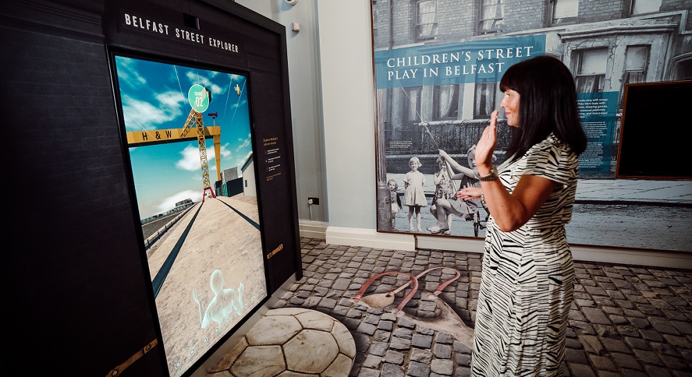 Woman playing Belfast Street Explorer game which uses gesture controlled interactive gaming.